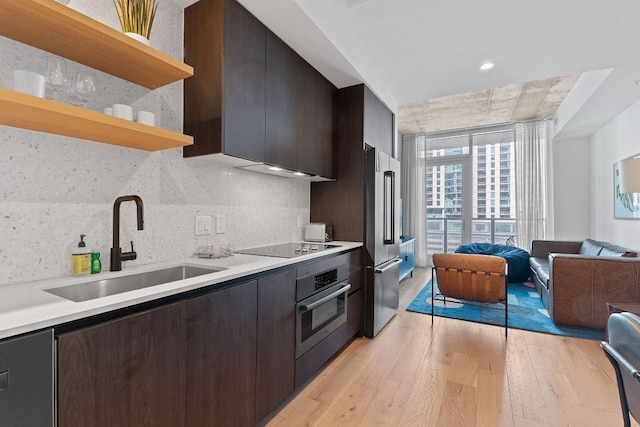 kitchen with light wood-type flooring, stainless steel appliances, light countertops, and open shelves