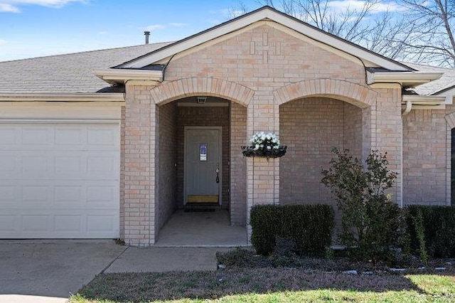 view of exterior entry featuring brick siding and an attached garage