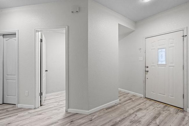 foyer entrance featuring a textured wall, baseboards, and wood finished floors