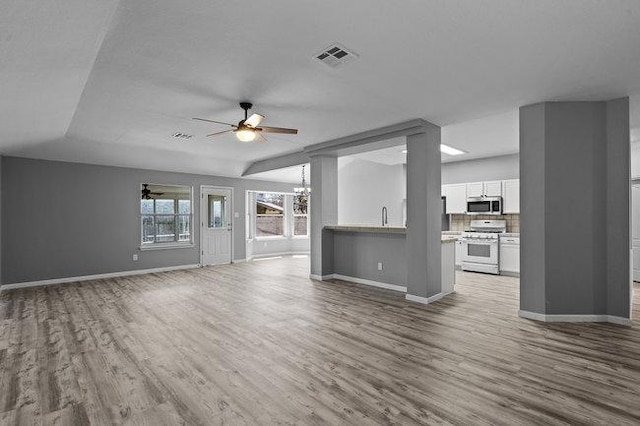 unfurnished living room with baseboards, wood finished floors, and ceiling fan with notable chandelier