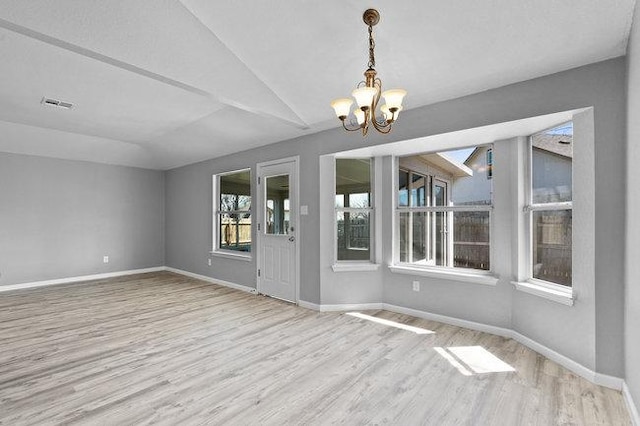 unfurnished room with visible vents, baseboards, a chandelier, vaulted ceiling, and wood finished floors