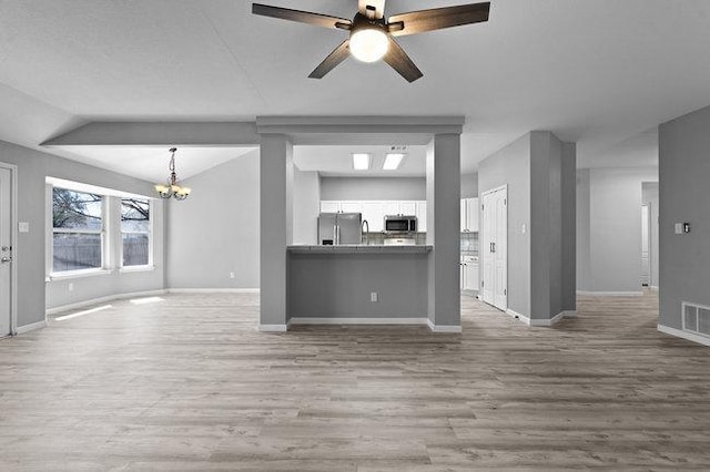 unfurnished living room featuring ceiling fan with notable chandelier, lofted ceiling, baseboards, and wood finished floors