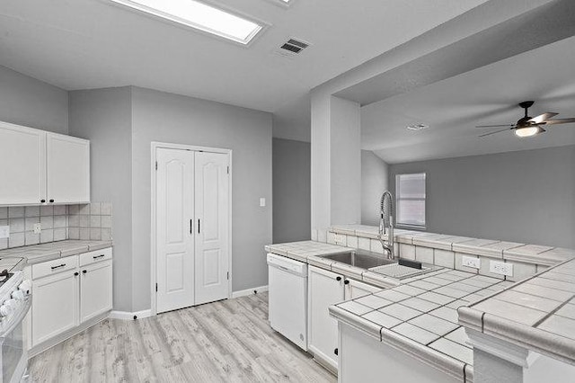 kitchen featuring white appliances, tile countertops, visible vents, a sink, and white cabinets