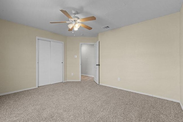 unfurnished bedroom featuring a ceiling fan, baseboards, visible vents, a closet, and light carpet