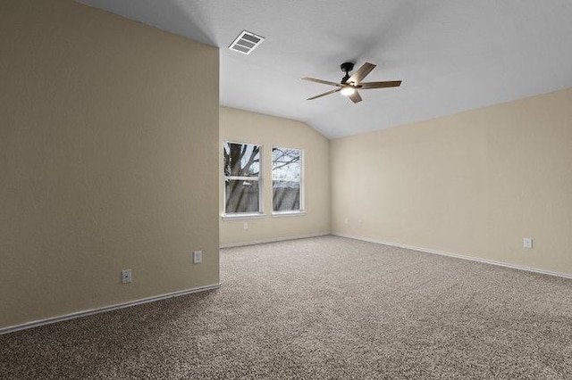 carpeted empty room with visible vents, baseboards, ceiling fan, and vaulted ceiling