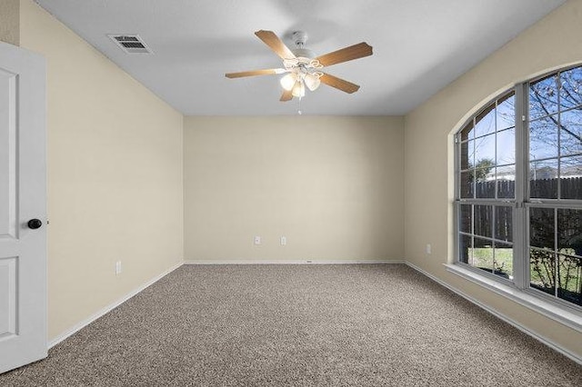 unfurnished room with visible vents, baseboards, carpet, and a ceiling fan