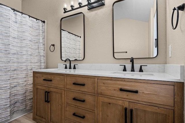 full bath with a sink, wood finished floors, and double vanity