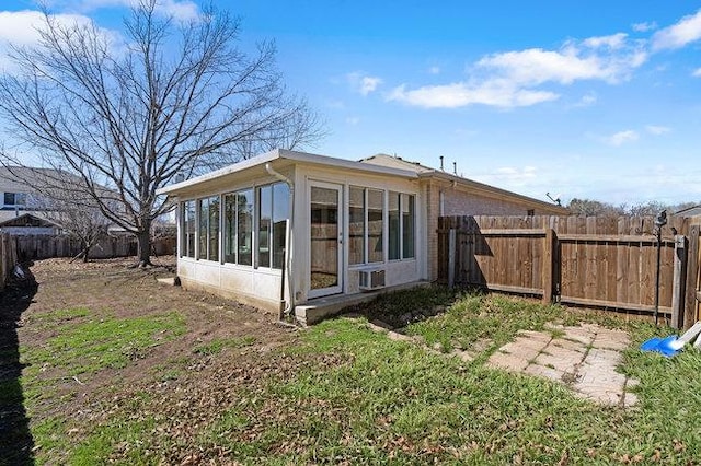 view of side of home with a fenced backyard, brick siding, and a sunroom