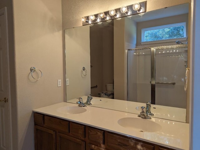 bathroom with a sink, an enclosed shower, and double vanity