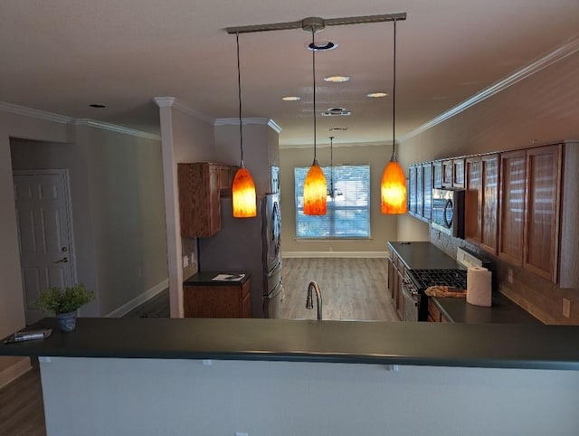 kitchen featuring stainless steel appliances, wood finished floors, baseboards, and ornamental molding