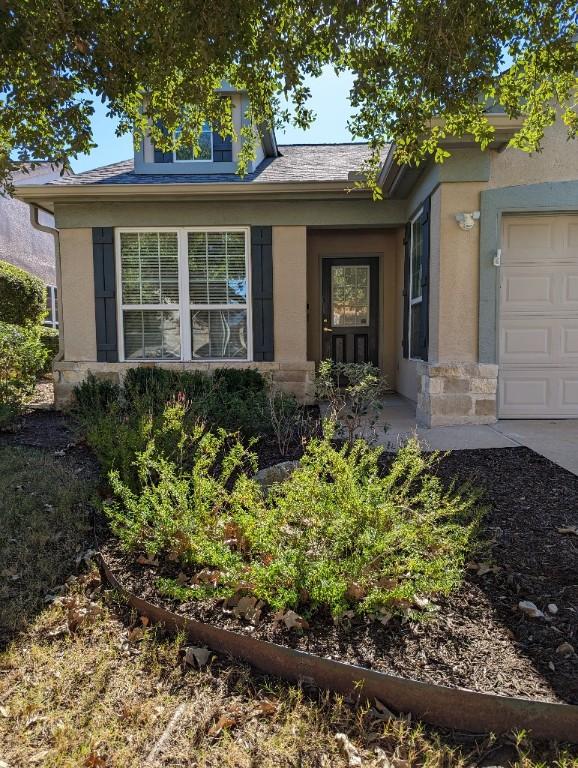 view of front of property featuring stone siding, stucco siding, and an attached garage