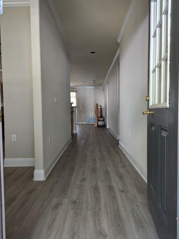 hall featuring wood finished floors, baseboards, and ornamental molding