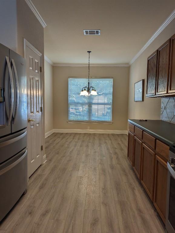 kitchen with crown molding, dark countertops, stainless steel fridge with ice dispenser, and light wood finished floors