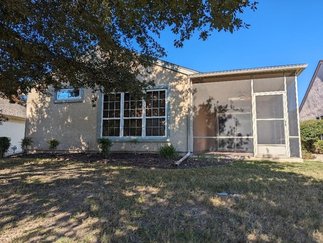 view of front of property featuring stucco siding, a front yard, and a sunroom