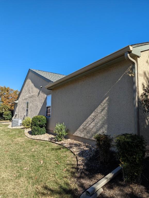 view of property exterior with stucco siding and a lawn