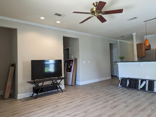 living area featuring visible vents, baseboards, light wood-style floors, and crown molding