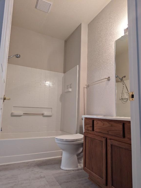 bathroom featuring visible vents, washtub / shower combination, toilet, a textured wall, and vanity