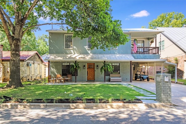 view of front of property featuring brick siding, a balcony, concrete driveway, and a front lawn