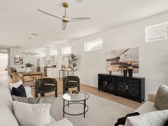 living area featuring light wood finished floors, visible vents, baseboards, and ceiling fan