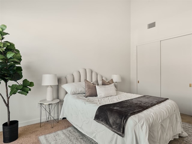 carpeted bedroom with visible vents, baseboards, and a closet