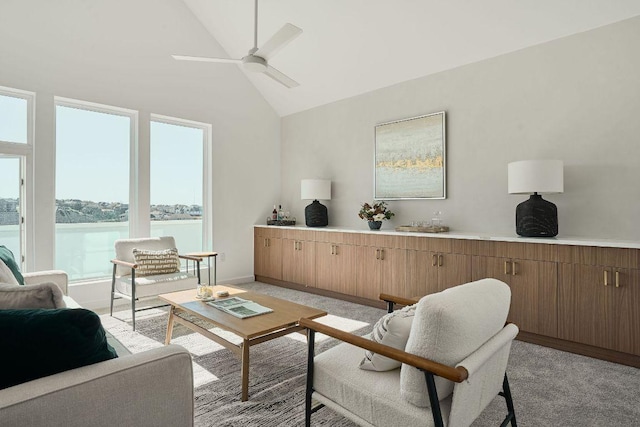 living area with light colored carpet, high vaulted ceiling, ceiling fan, and a water view