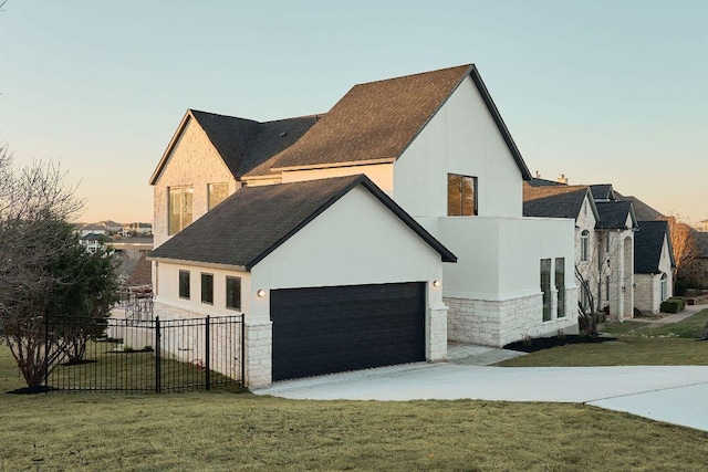 view of side of property featuring fence, stucco siding, a garage, a yard, and stone siding