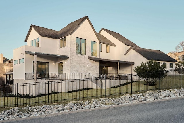 view of front of property featuring a fenced front yard, stone siding, and stucco siding