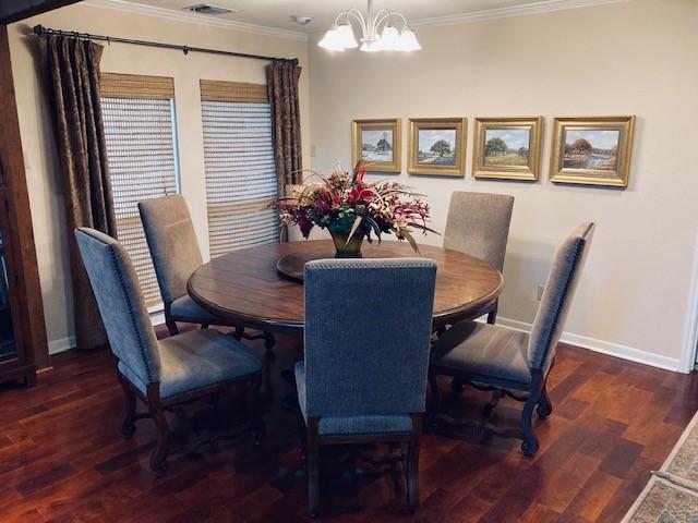 dining space featuring wood finished floors, an inviting chandelier, and ornamental molding