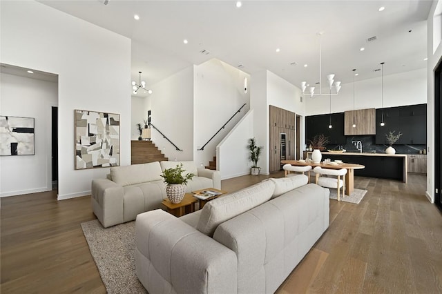 living area featuring a notable chandelier, stairs, a high ceiling, and wood finished floors