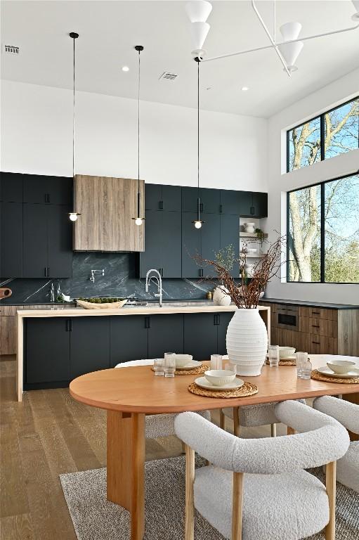 kitchen with visible vents, light wood finished floors, modern cabinets, light countertops, and decorative backsplash