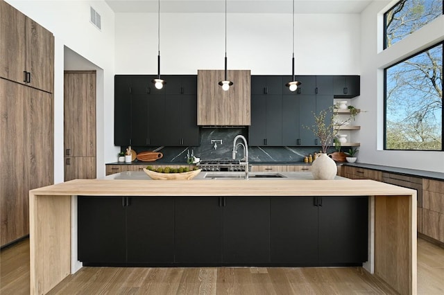 kitchen featuring a sink, visible vents, modern cabinets, and a towering ceiling