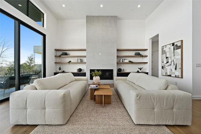 living room with a high ceiling, wood finished floors, and a tiled fireplace