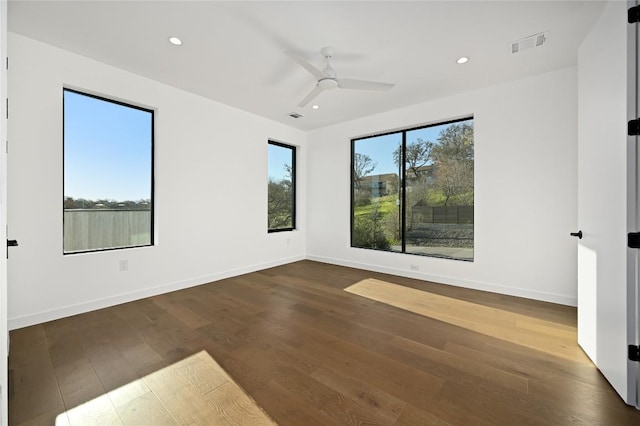 unfurnished room featuring a wealth of natural light, visible vents, baseboards, and wood finished floors