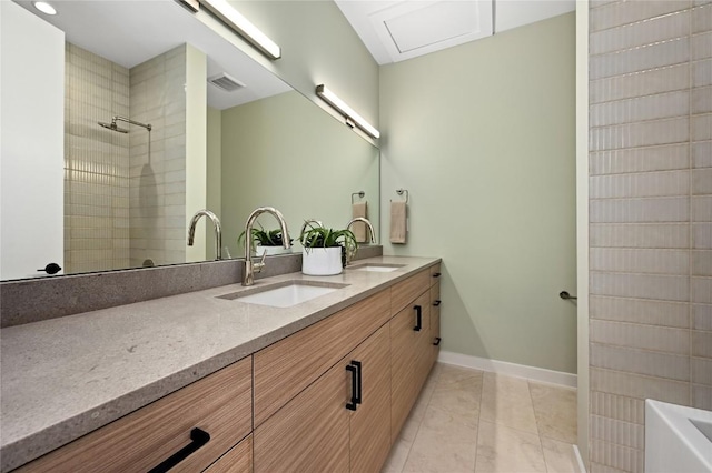 bathroom featuring a tile shower, visible vents, double vanity, and a sink