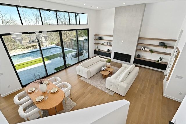 living room featuring recessed lighting, a large fireplace, baseboards, and wood finished floors