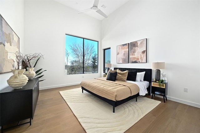 bedroom featuring baseboards, a high ceiling, and wood finished floors