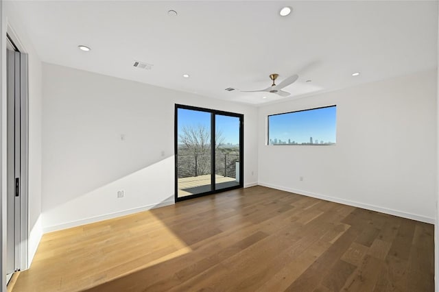 unfurnished room featuring recessed lighting, wood finished floors, visible vents, and baseboards