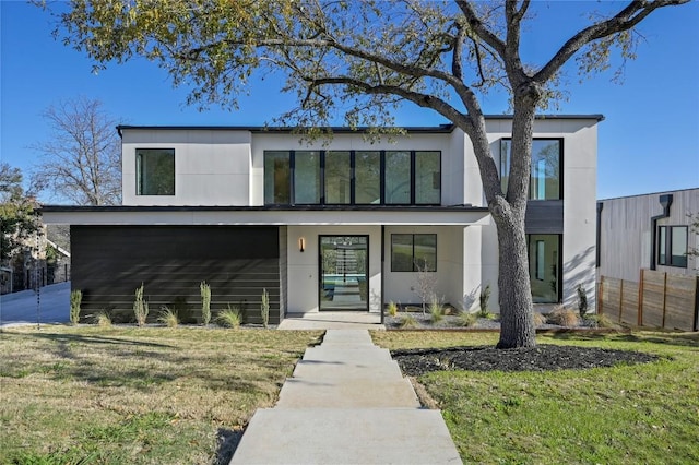 contemporary house featuring stucco siding and a front lawn