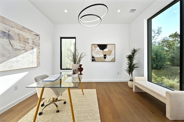 office space with wood finished floors, visible vents, and a healthy amount of sunlight