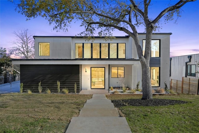 view of front of property featuring stucco siding, a lawn, and fence