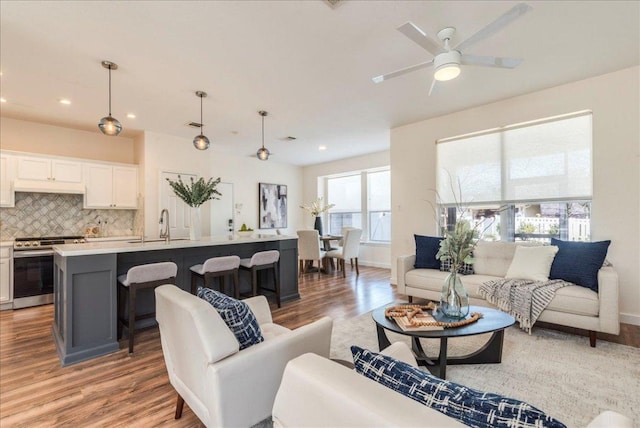 living room featuring recessed lighting, baseboards, light wood-style flooring, and a ceiling fan