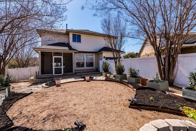 back of house with a garden, a gate, a fenced backyard, and a sunroom