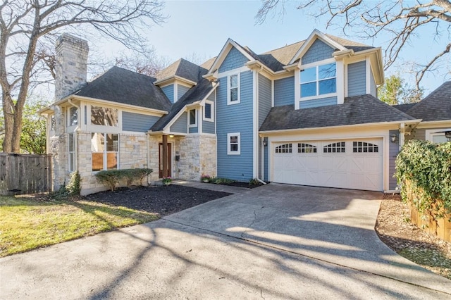 5603 Clay Ave Unit B, Austin, TX 78756 - view of front of home with concrete driveway, a chimney, stone siding, an attached garage, and a shingled roof