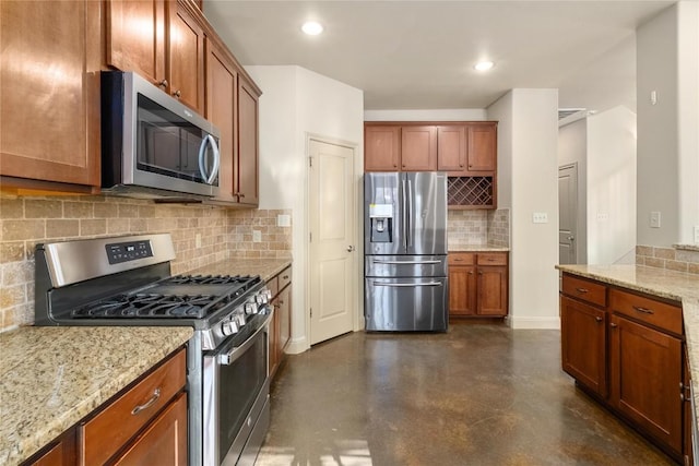 kitchen with backsplash, light stone countertops, concrete flooring, brown cabinetry, and stainless steel appliances