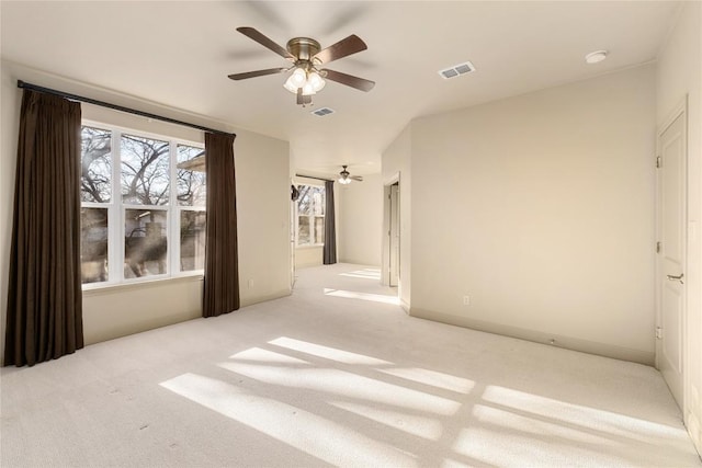 carpeted empty room with visible vents, baseboards, and a ceiling fan