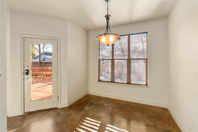 unfurnished dining area with unfinished concrete floors and baseboards