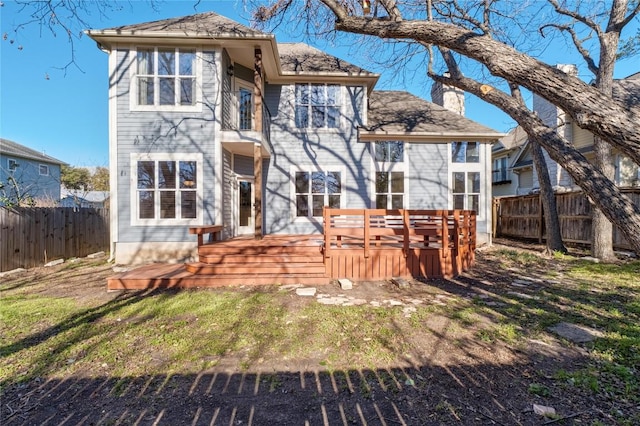 rear view of house with a wooden deck, a yard, a chimney, and fence