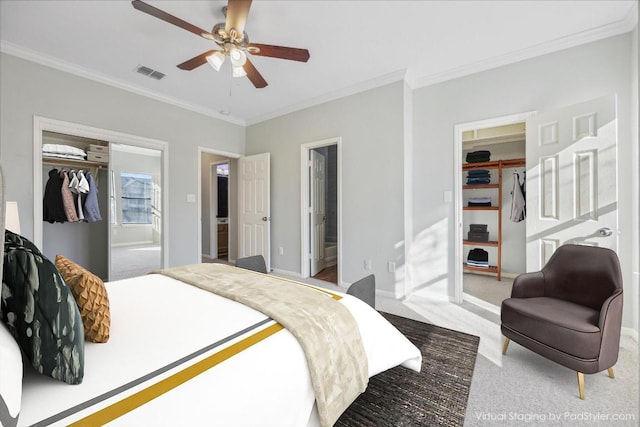 carpeted bedroom featuring a closet, visible vents, a spacious closet, and ornamental molding