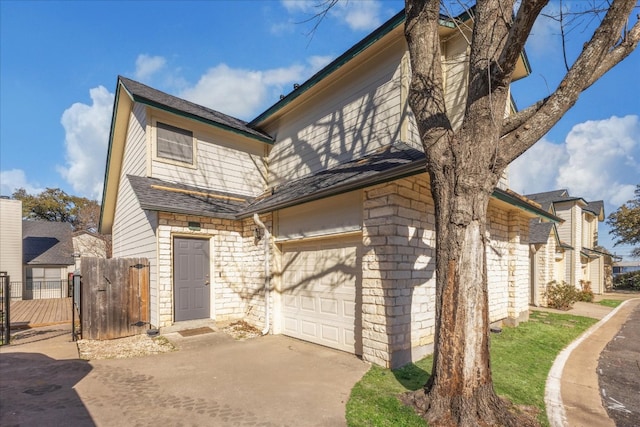 view of front of property featuring fence, driveway, stone siding, an attached garage, and a gate