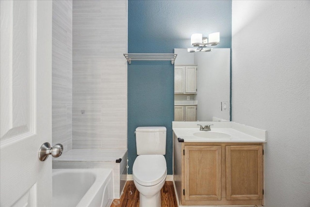 bathroom with toilet, vanity, an inviting chandelier, and a textured wall